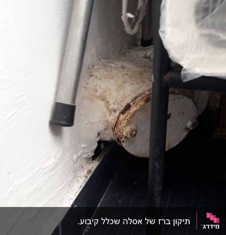 צינור חלוד עם ברגים בקיר לבן